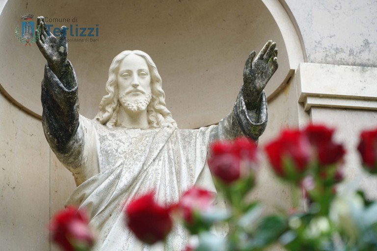 Le rose donate al cimitero con il Cristo benedicente